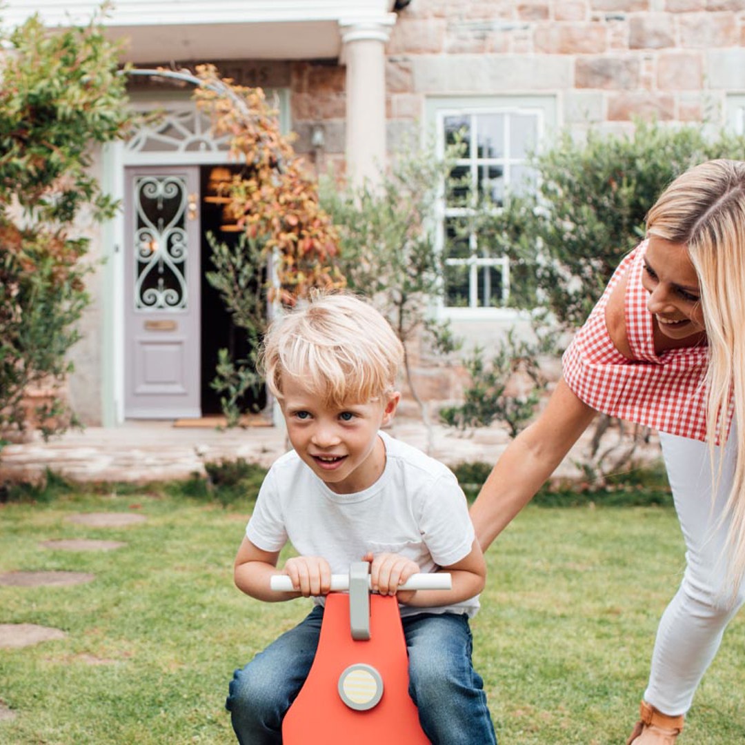 Woman with child on toy car in garden