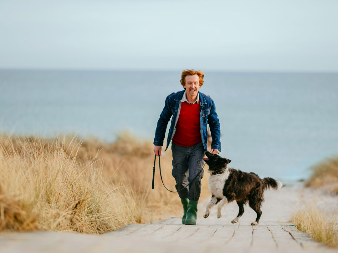 Man with dog on path by beach