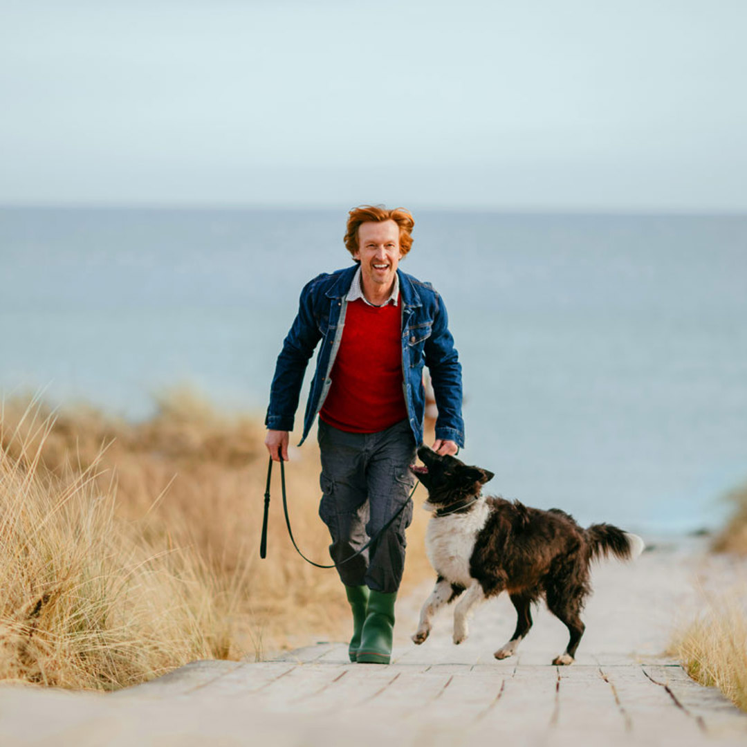 Man with dog on path by beach