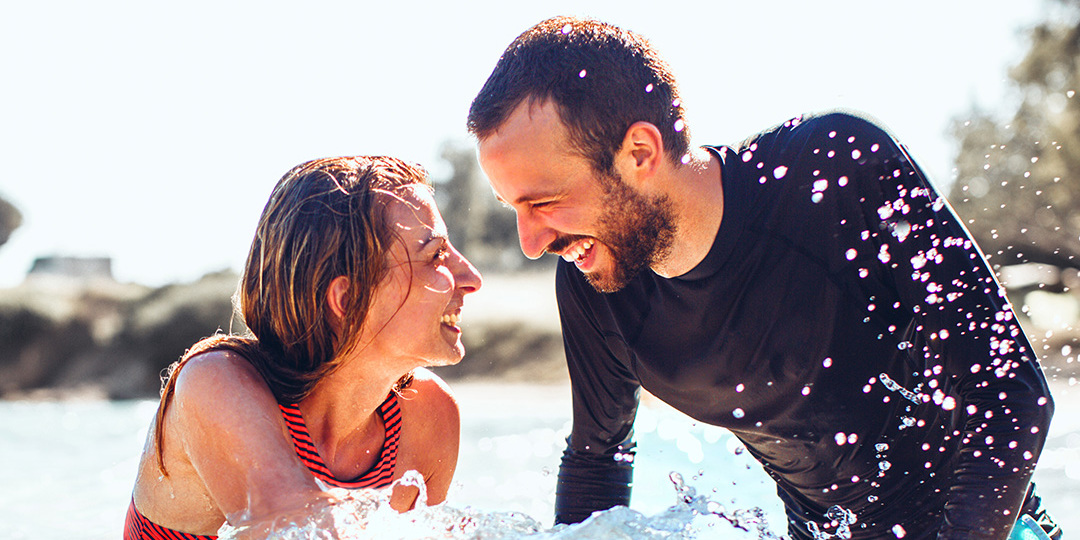 Man and woman smiling on surfboard in sea