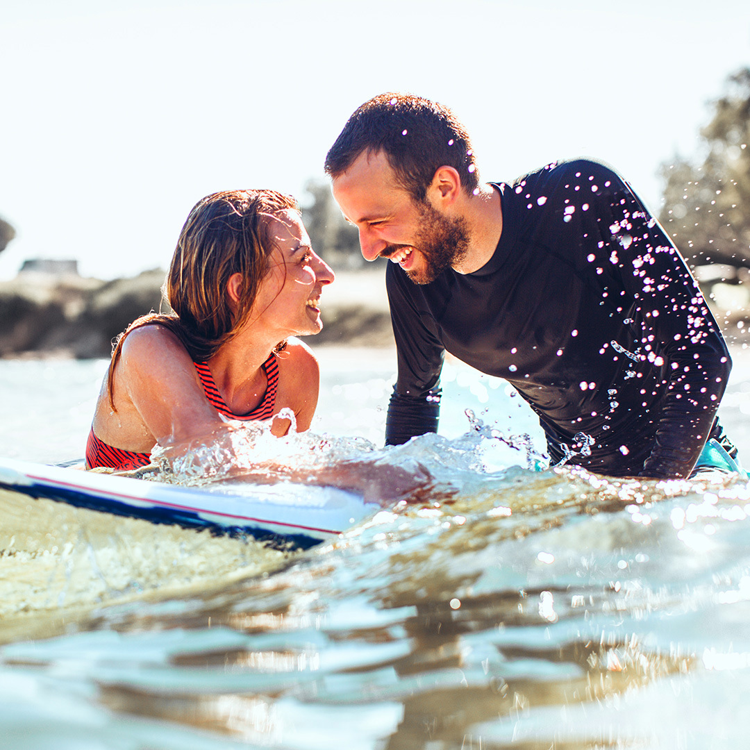 Man and woman smiling on surfboard in sea