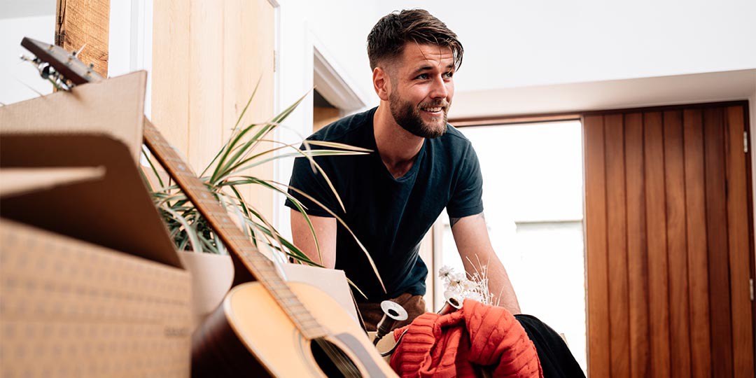Man holding removals box next to guitar