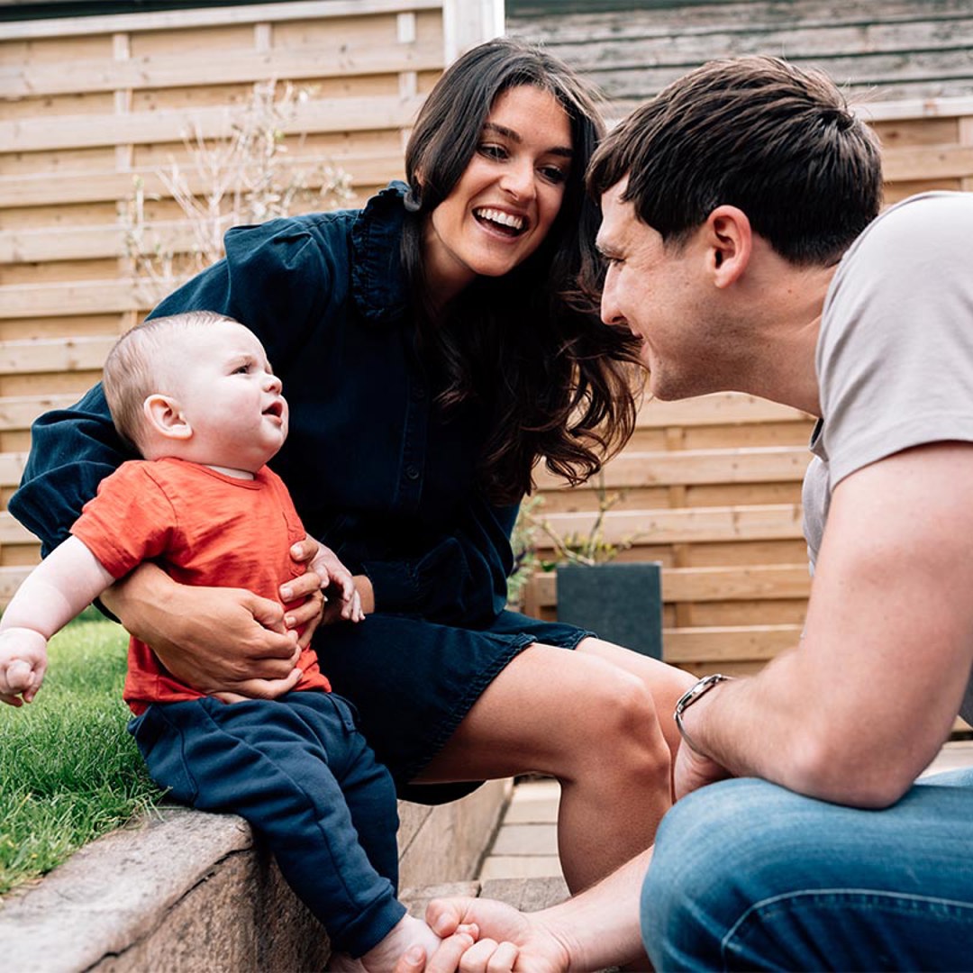 Man and woman sat in garden with baby