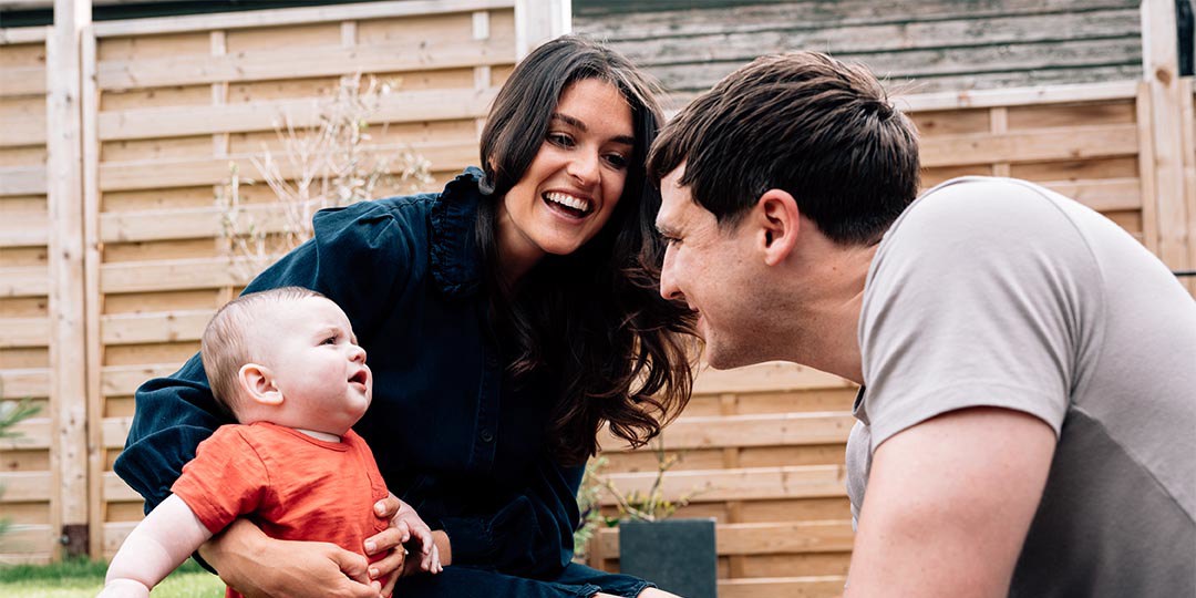 Man and woman sat in garden with baby