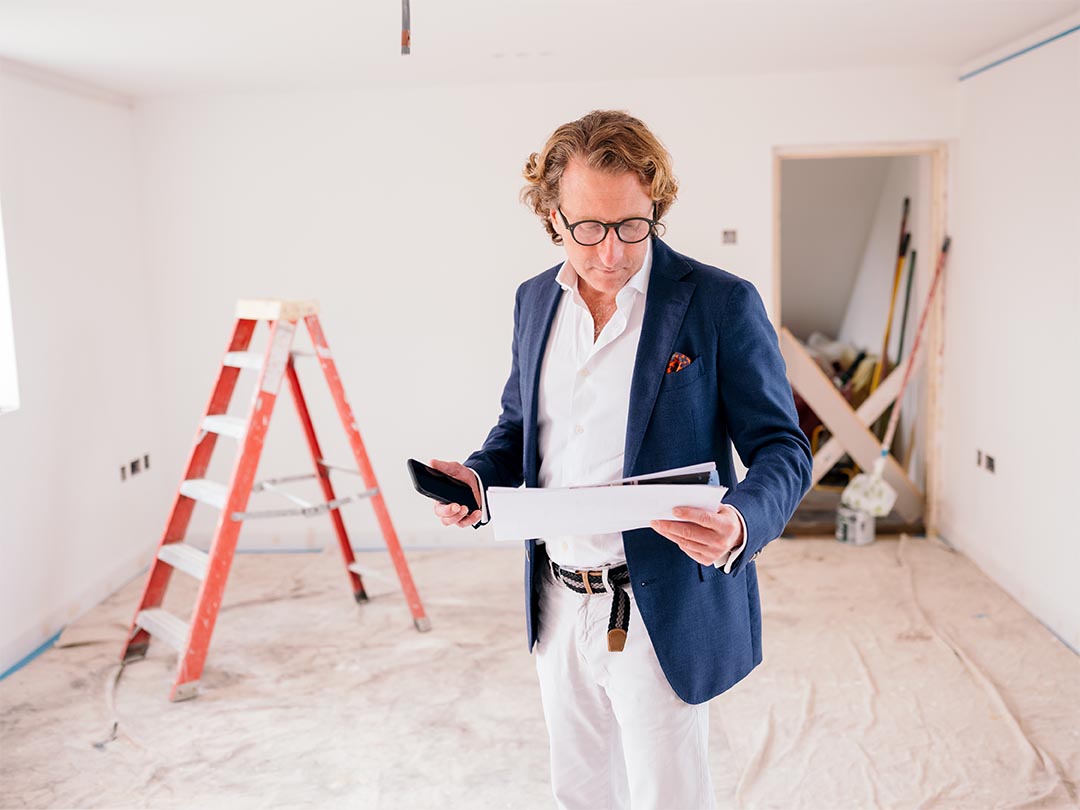 Man in room looking at paperwork in front of stepladder