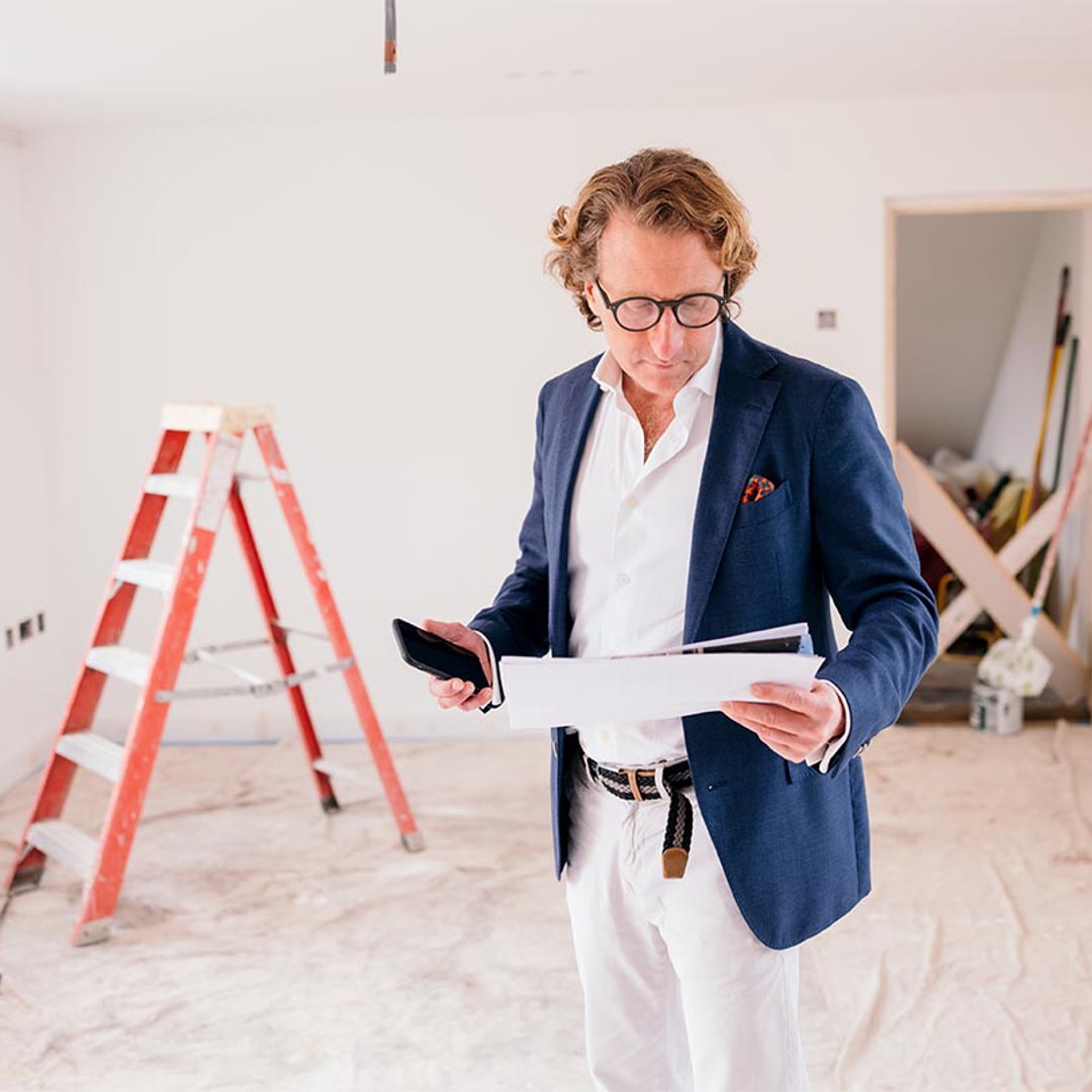 Man in room looking at paperwork in front of stepladder