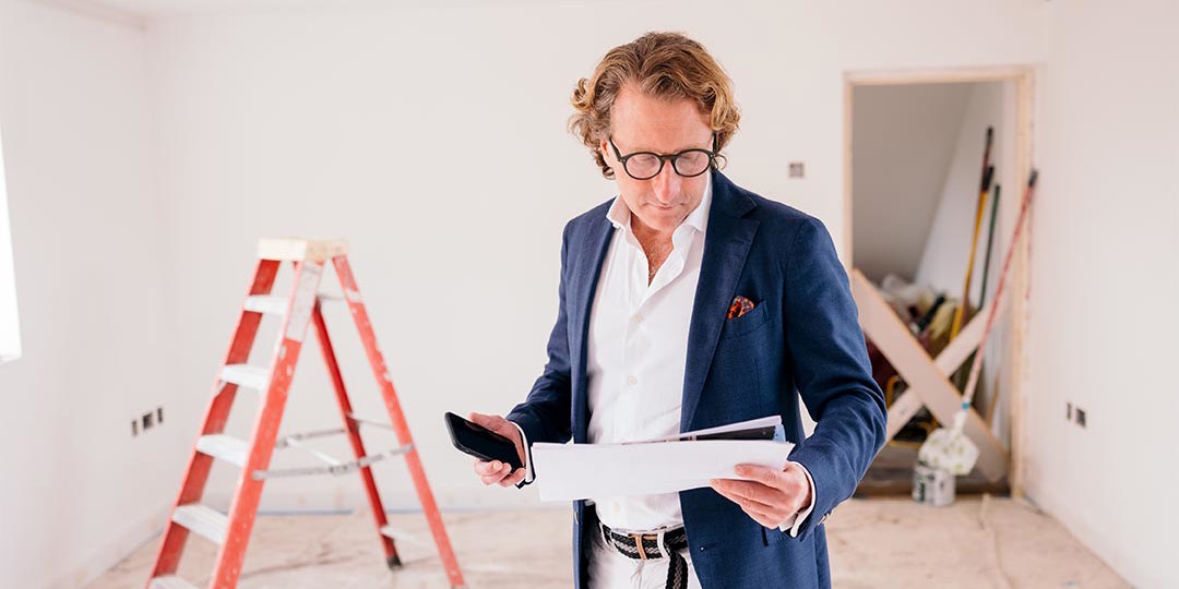 Man in room looking at paperwork in front of stepladder
