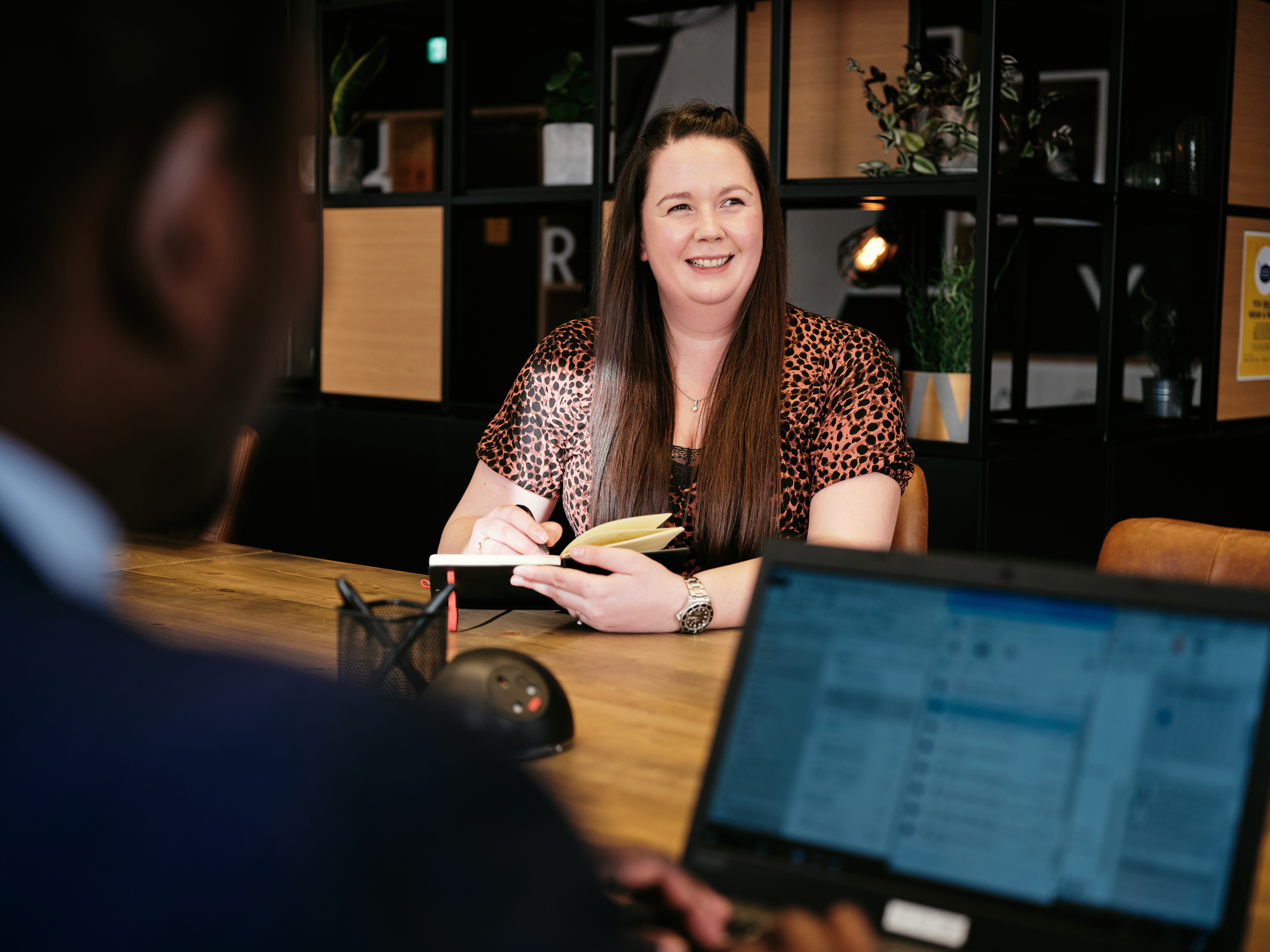Woman sat at co-working desk in work cafe with notepad and pen