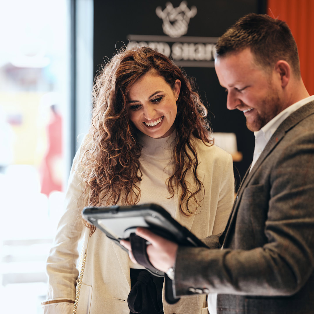 Man with iPad stood talking to woman in Work Cafe