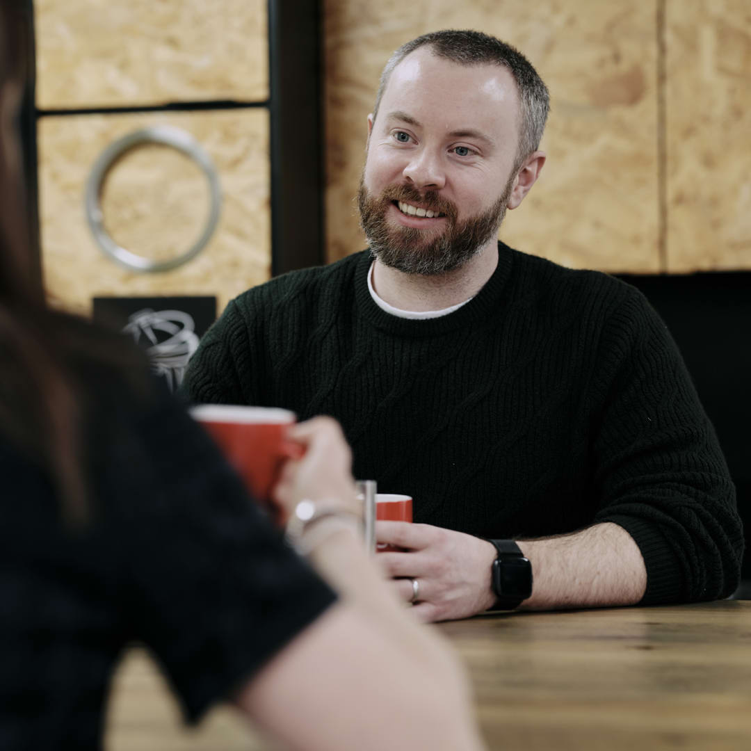 Man sat opposite woman at table with red mug