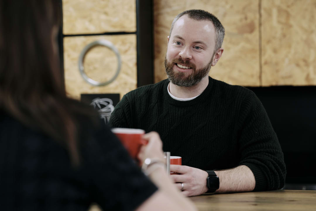 Man sat opposite woman at table with red mug