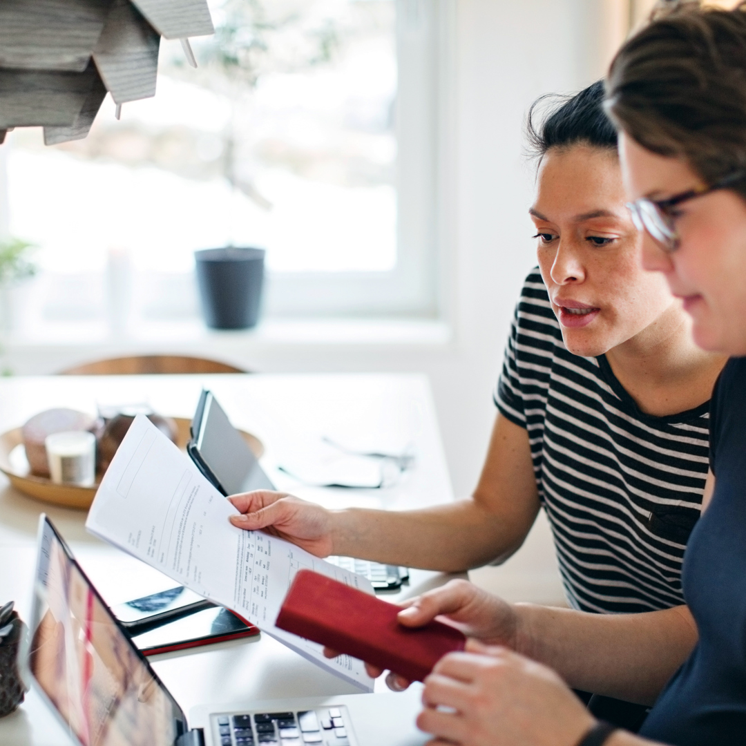 2 women sat at lap top with paperwork