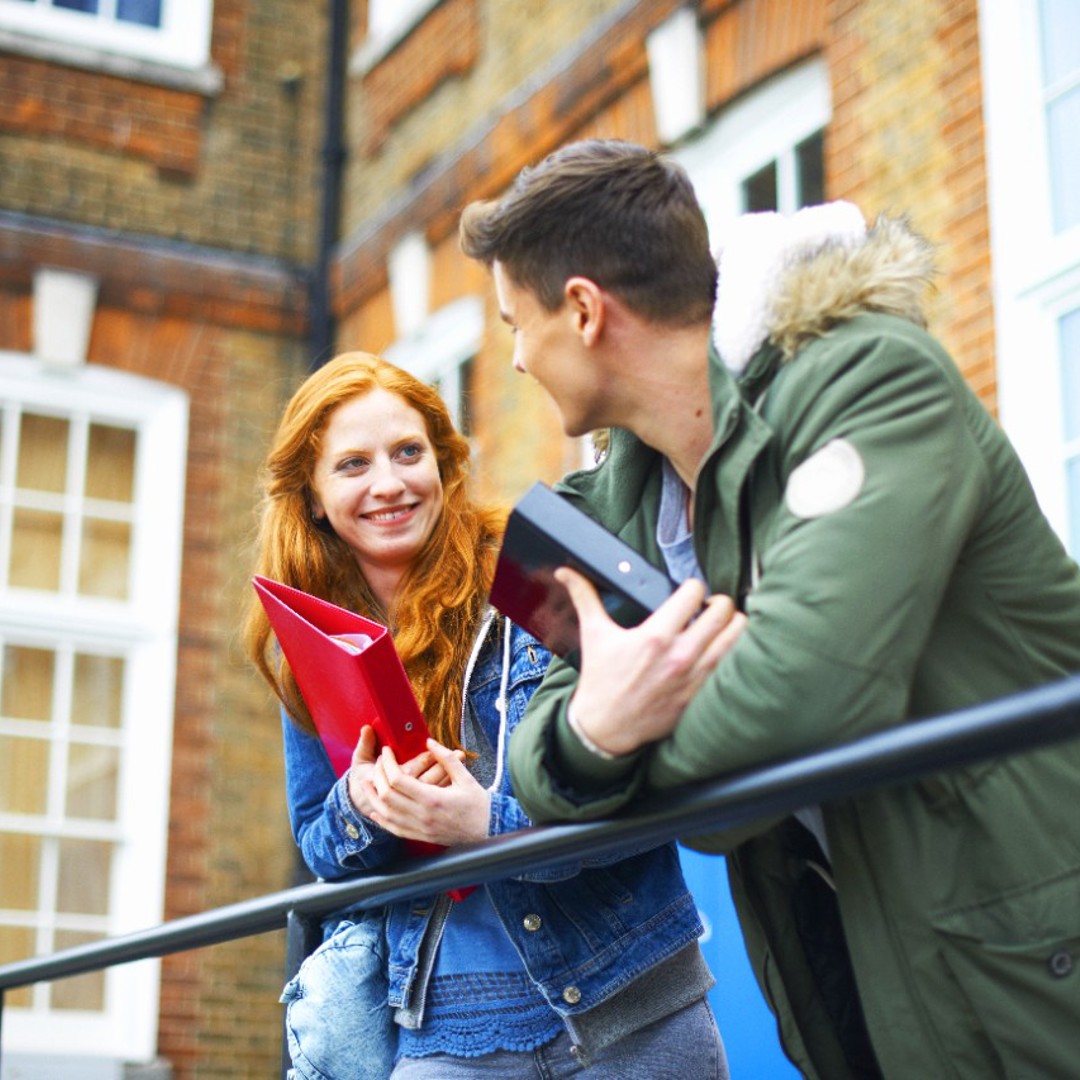 Girl and boy leaning over railings with files